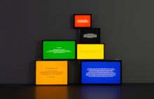Pile of colored lightboxes with texts againts wall gallery