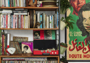 Shelf of books & vinyl records with player with movie poster on right of photo