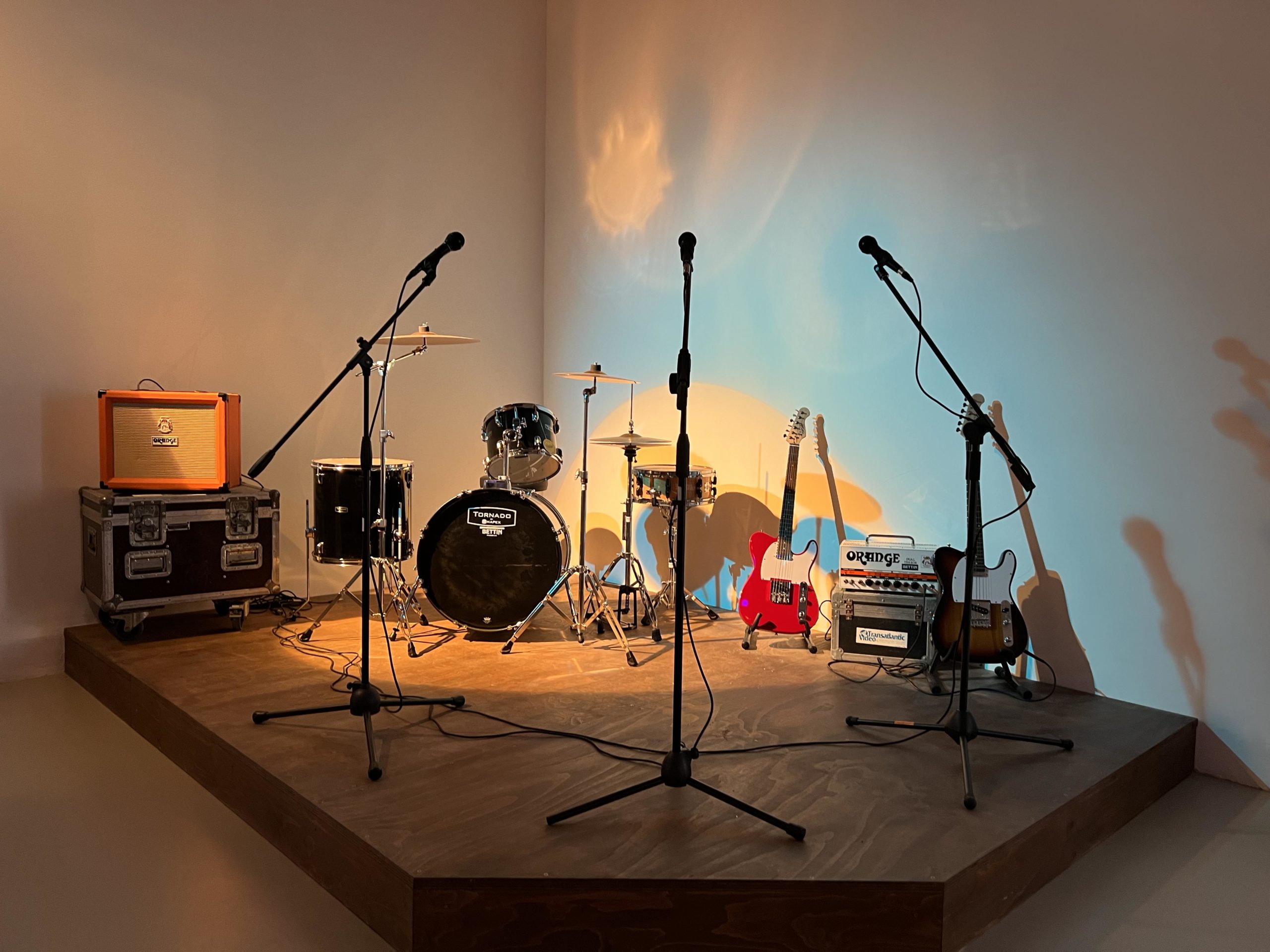 band instruments on elevated platform: 3 microphones, 2 guitars and a drum kit