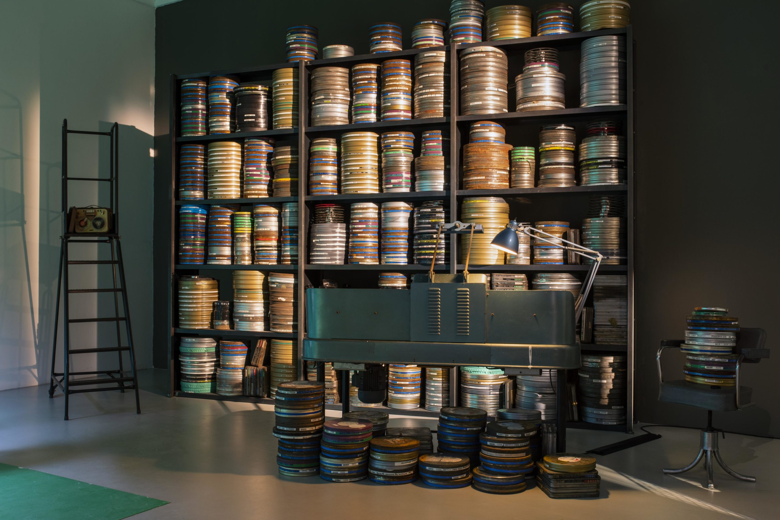 shelves of film canisters behind a film editing workstation