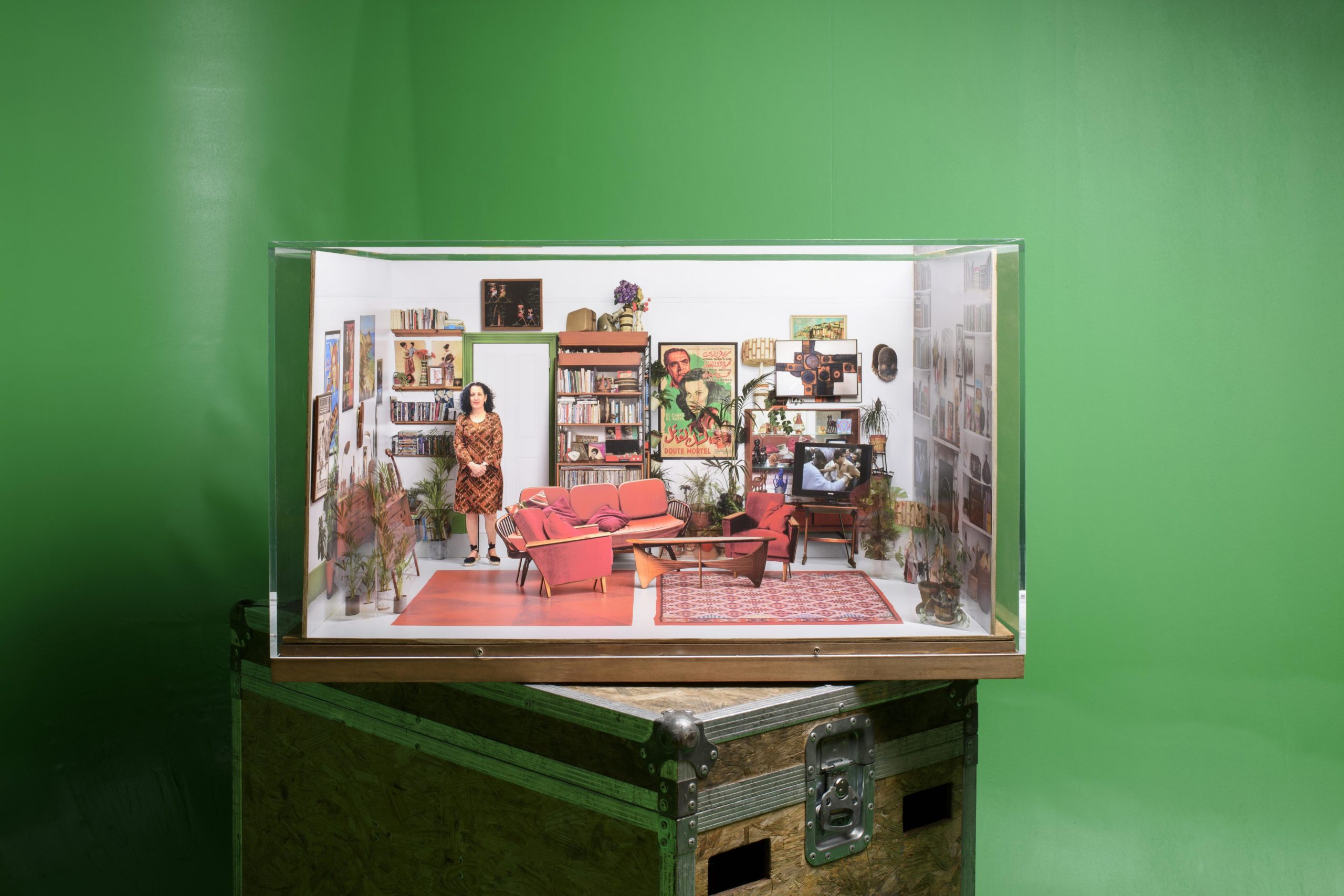 Paper miniature of a living roomset (complete with paper cutout of person) is seen in close up with green screen as background