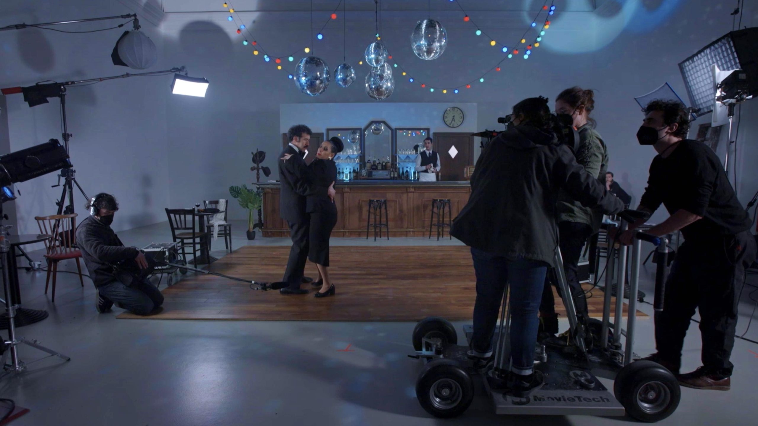 filmed by a camera crew a man and woman dance on a bar/cafe set