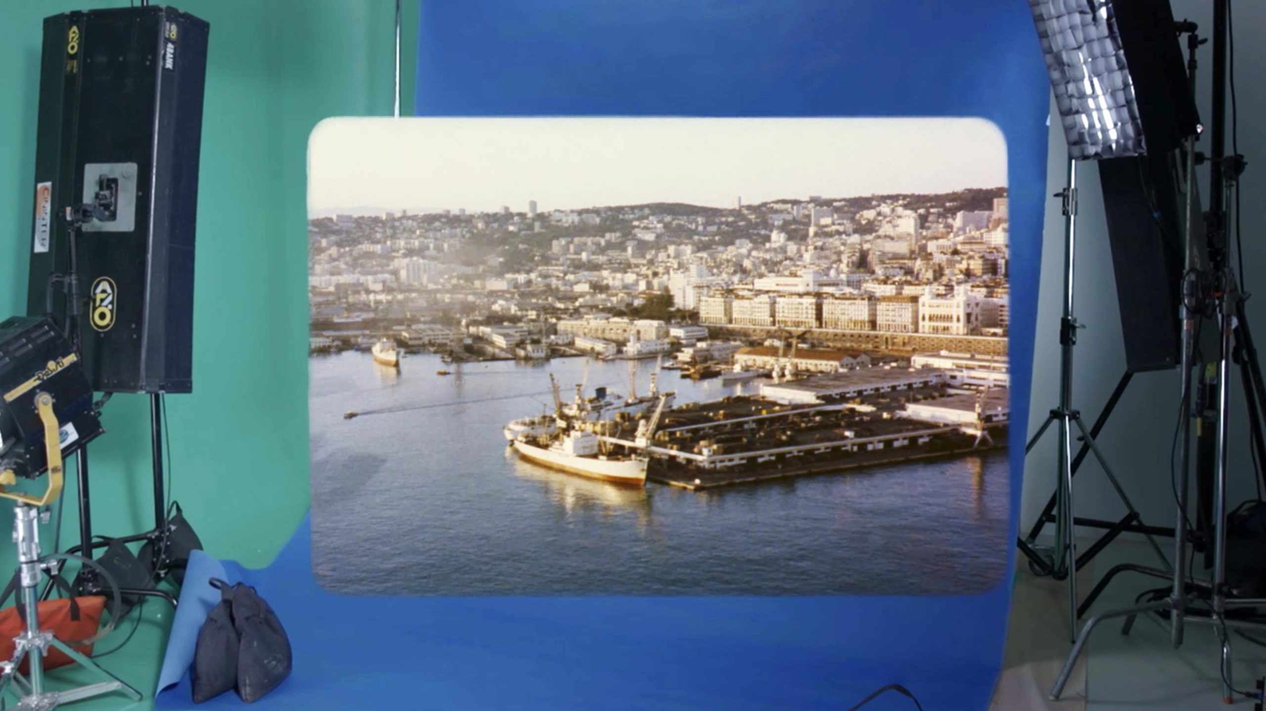 photo of harbour is seen projected onto blue and green screen background surround by film set lighting rigs